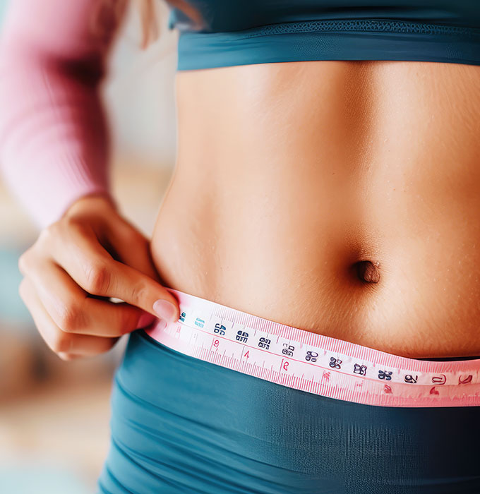 Woman measures waistline with flexible measuring tape